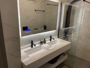 ein Badezimmer mit einem weißen Waschbecken und einem Spiegel in der Unterkunft Angel's Apartment Volos in Volos