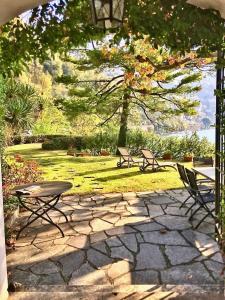 a patio with two chairs and a table and a tree at On Lake Villa Cicci e Sandro in Bellano +11 photos
