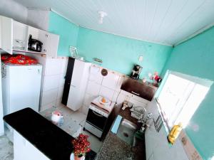 uma pequena cozinha com paredes azuis e eletrodomésticos brancos em Nosso Sonho em Rio das Ostras
