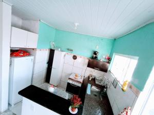 uma pequena cozinha com paredes azuis e eletrodomésticos brancos em Nosso Sonho em Rio das Ostras mais 4 fotografias