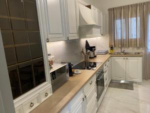 eine Küche mit weißen Schränken und einem Herd mit Backofen in der Unterkunft Angel's Apartment Volos in Volos