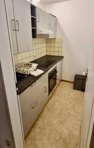 a kitchen with white cabinets and a black counter top at GMA Apartment B16 in Lahr