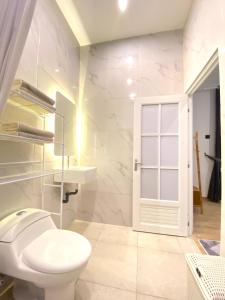 a white bathroom with a toilet and a window at Luxor Villa Private Pool in Ngaglik