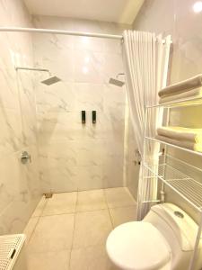a white bathroom with a shower and a toilet at Luxor Villa Private Pool in Ngaglik +8 photos