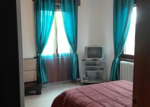 1 dormitorio con cortinas azules, 1 cama y TV en B&B River, en Ascoli Piceno