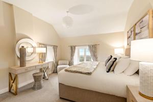 a bedroom with a large white bed and a desk at Great Easton Lodge in Great Easton