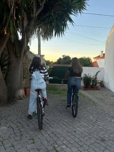 two women riding bikes down a brick sidewalk at O Cantinho do Pedro in Tolosa +13 photos