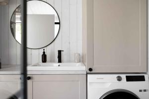 a white bathroom with a sink and a mirror at Newly Built Luxury House On Bornholm in Hasle