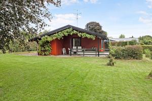 a red house with a picnic table in a yard at Holiday Home 100 Meters From A Lovely Beach in Tranekær +11 photos