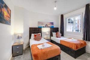 a bedroom with two beds and a window at Eastons 2 Bedroom Apartment with Sofa Bed in High Wycombe