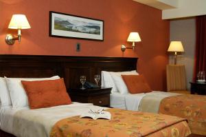 ein Hotelzimmer mit 2 Betten und orangefarbenen Wänden in der Unterkunft Hotel Quijote in El Calafate
