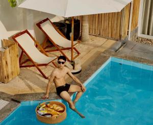 a man sitting in a swimming pool with a basket of food at Inner Peace Homestay Phan Thiet in Phan Thiet