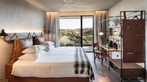 a bedroom with a bed and a desk and a window at Puro Dão Hotel & Spa in Nelas