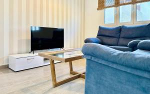 a living room with a blue couch and a tv at Canaryislandshost l Girasol in Punta de Mujeres