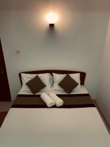 1 cama con 2 almohadas y una luz en la pared en Seasons Villa Sigiriya, en Sigiriya