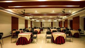 a banquet hall with tables and chairs in a room at Sakthi River Resort in Pollāchi