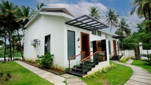 a white house with a pathway leading to it at Sakthi River Resort in Pollāchi