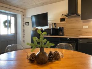a wooden table with a vase with pine cones on it at Au charmant chablis in Champagnole