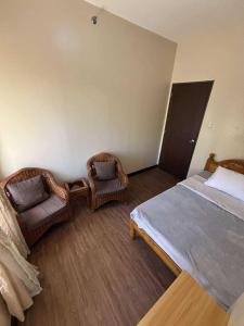1 Schlafzimmer mit 2 Korbstühlen und 1 Bett in der Unterkunft Outlook Ridge Residences VY in Baguio City