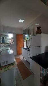 カラグアタトゥーバにあるMassaguaçu Cocanha "150 mts Praia "のキッチン(白い家電製品、黒いカウンタートップ付)