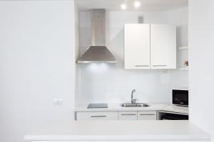Una cocina blanca con gabinetes blancos y un fregadero. en Ocean view & Pool Los Cristianos Summerland, en Los Cristianos