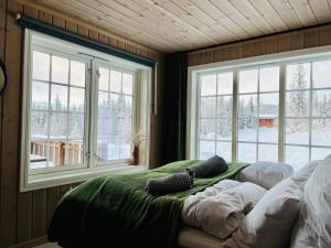 1 dormitorio con 2 ventanas y 1 cama con almohadas en Beitobygda Getaway ,Nature and Luxury, en Beitostølen