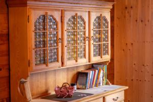 a wooden cabinet with glass windows and a shelf with books at Chalet Daheim - Ferienwohnung OG in Reckingen - Gluringen +25 photos