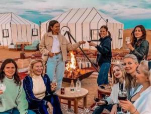 a group of women sitting around a fire in front of a tent at Sunshine luxury tent in Merzouga