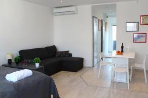 Una sala de estar con un sofá negro y una mesa. en Broadway Center Rooftop View Apartment, en Budapest