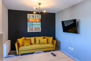 - un salon avec un canapé jaune et une télévision dans l'établissement KOA - THE BOX, à Braşov