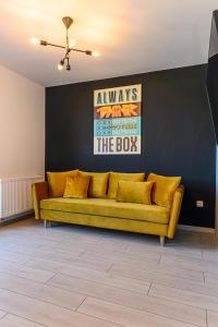 - un canapé jaune dans une pièce dotée d'un mur noir dans l'établissement KOA - THE BOX, à Braşov