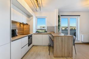 une cuisine avec des armoires blanches et une table avec des chaises dans l'établissement KOA - THE BOX, à Braşov