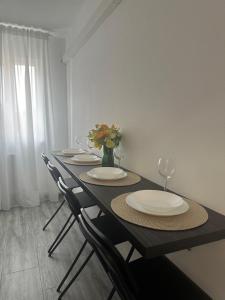 a table with chairs and plates and a vase with flowers at Apartament 2 Cam Cetate in Alba Iulia +2 photos