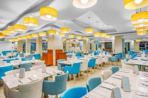 a dining room with white tables and blue chairs at Glaros Beach Hotel in Hersonissos +37 photos