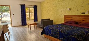 a bedroom with a bed and a chair and a window at Hotel Robinson Plage in Lomé +72 photos