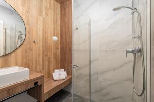 ein Badezimmer mit Dusche, Waschbecken und Spiegel in der Unterkunft Jantaris - City Apartments in Mielno + 45 Fotos