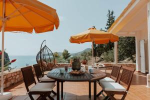 a table with chairs and an umbrella on a patio at Kastraki Sea View in Tolo