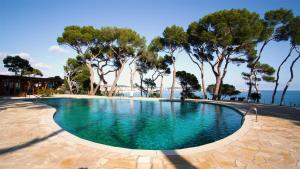 a swimming pool with trees and the ocean in the background at Apartamento EDEN MAR I by HR COSTABRAVA in Calonge