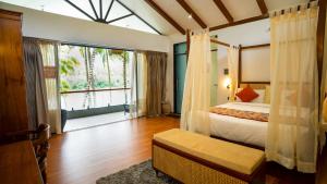 a bedroom with a bed and a large window at Sakthi River Resort in Pollāchi