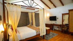 a bedroom with a bed and a desk and a television at Sakthi River Resort in Pollāchi