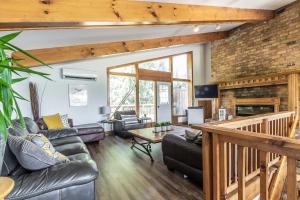 a living room with leather furniture and a brick wall at Birch View- Balcony-Backyard-Parking-Sauna-Sleeps 20 in Blue Mountains