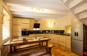 eine große Küche mit Tisch und Kühlschrank in der Unterkunft La bichonelle - marronnier pour 2 in Saint-Crépin-et-Carlucet