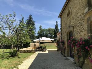 a stone building with a table and an umbrella at Le petit fort in La Roque-Gageac