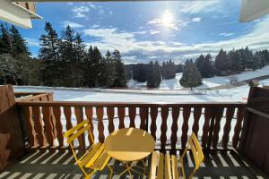 ein gelber Stuhl auf einem Balkon mit einer schneebedeckten Piste in der Unterkunft Chaleureux studio au pied des pistes - Le refuge in Les Déserts