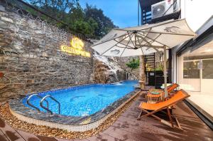 a swimming pool in front of a wall with an umbrella at Green LP Hotel & Apartment in Vung Tau