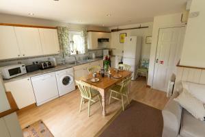 a kitchen with a wooden table with chairs and a sink at Badgers Den, a beautiful log cabin in a secluded valley close to the beach in Bantham