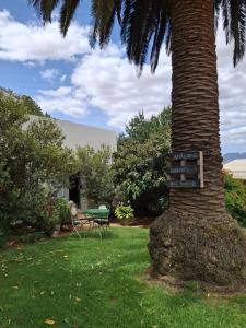 a sign on a palm tree next to a bench at Blou Porselein Guestfarm in Hermon