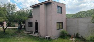a small house in a field next to a building at Cabaña el diquecito in La Calera