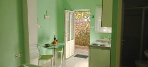 Una cocina con paredes verdes y una mesa y una puerta. en Apartments Mara, en Mali Lošinj