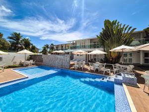 a swimming pool with chairs and umbrellas next to a building at Hotel Vivenda dos Corais in Porto De Galinhas